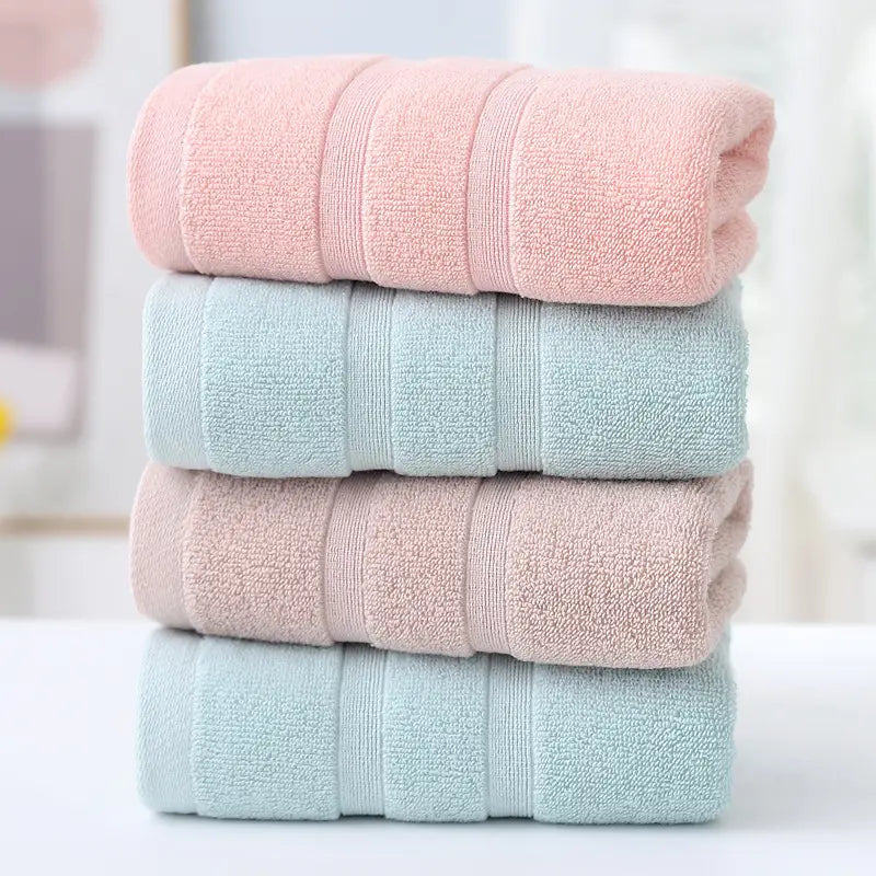 Stack of four folded towels in pink, light blue, and pastel pink on a blurred background