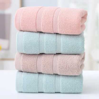 Stack of four folded towels in pink, light blue, and pastel pink on a blurred background