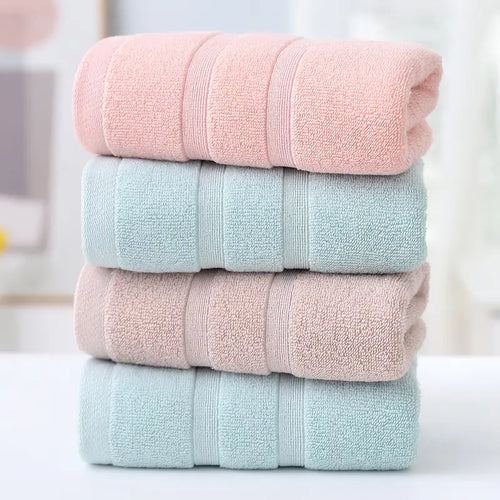 Stack of four folded towels in pink, light blue, and pastel pink on a blurred background