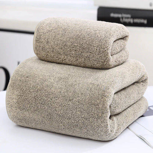 Two beige towels stacked on a white surface with a blurred background