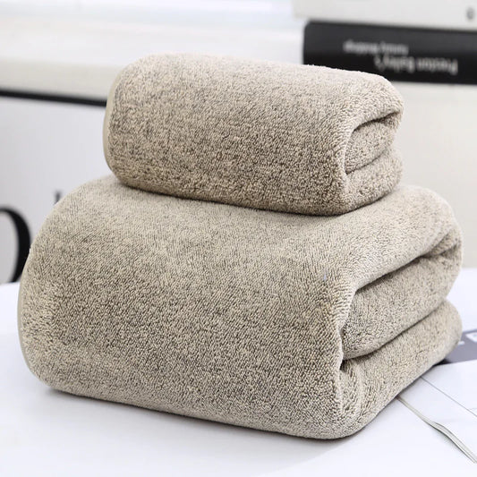 Two beige towels stacked on a white surface with a blurred background