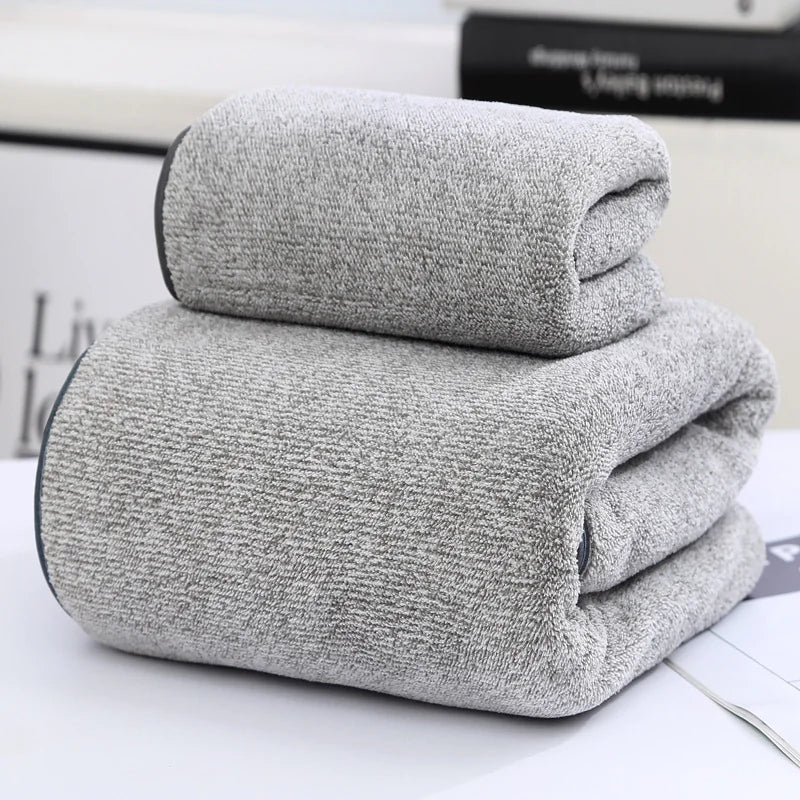 Two folded gray towels on a white surface with a blurred background
