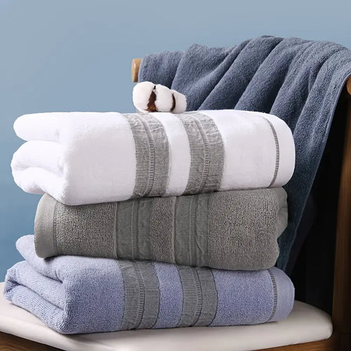 Stack of folded towels in white, gray, and blue on a wooden surface with a blue wall background.