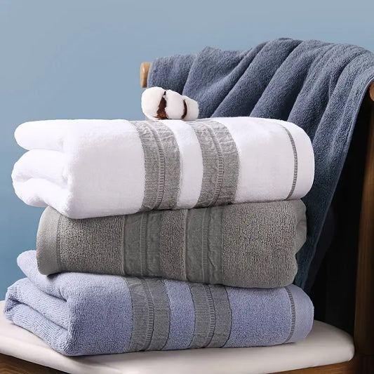 Stack of folded towels in white, gray, and blue on a wooden surface with a blue wall background.